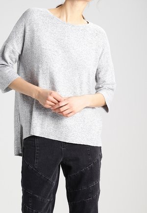 Graues, leichtes Strickoberteil mit weitem Ausschnitt und Dreiviertelärmeln; strukturierter Stoff; kombiniert mit schwarzen Hosen mit diagonaler Naht.