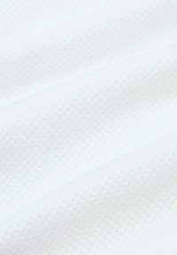 Teksturowana biała tkanina z geometrycznym wzorem, z wypukłymi elementami i gładkim wykończeniem, układająca się w miękkie fałdy.