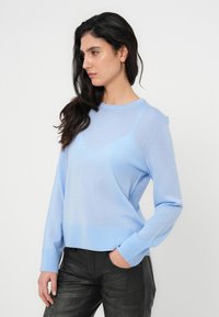 Ανοιχτό μπλε, μακρυμάνικο πλεκτό πουλόβερ με ριμπ μανσέτες και τελείωμα. Λείο ύφασμα, στρογγυλή λαιμόκοψη, ελαφρώς άνετη εφαρμογή.