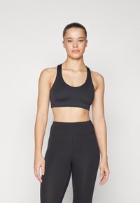 Top corto deportivo negro con tirantes anchos y escote redondeado, combinado con leggings negros de cintura alta, ambos con una textura suave.