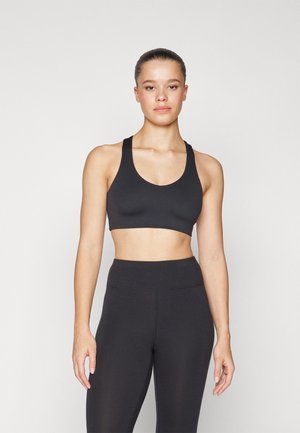 Svart atletisk crop topp med brede stropper og rund hals, kombinert med høy midje svarte leggings, begge med en glatt tekstur.