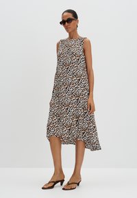 Bloemrijke jurk met een mix van bruine, witte en blauwe patronen, zonder mouwen, asymmetrische zoom, gemaakt van lichte stof.