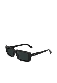 Ochelari de soare rectangle negri cu lentile întunecate, finisaj mat și o accente de logo distinctiv pe tâmplă. Design geometric simplu.