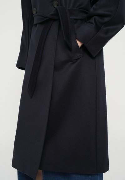 Navy blue coat made of textured fabric, featuring a belt and double buttons, with a knee-length design and side pockets.