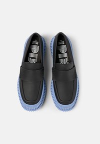 Scarpe slip-on nere con tomaia in pelle liscia e suola in gomma azzurro chiaro. Presentano una fascia larga sulla parte superiore e una suola testurizzata.