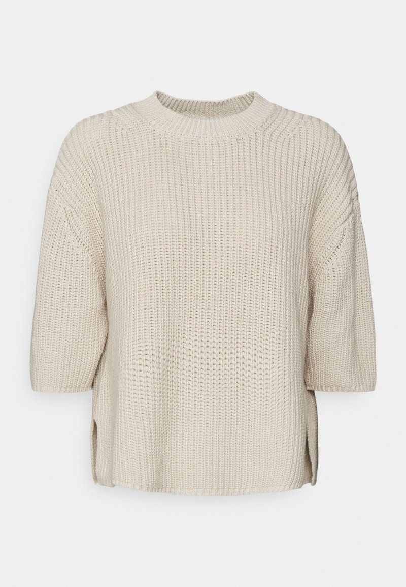 Maglione beige lavorato a maglia con scollo rotondo, maniche corte e spacchi laterali. Presenta un tessuto strutturato per una maggiore profondità.