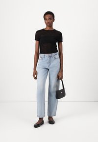 Svartstripet kortermet topp, lyseblå høyt liv rette jeans, svarte leiligheter, og en liten svart håndbag med en aksent.