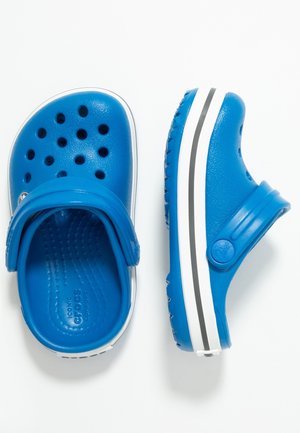 Coppia di zoccoli blu con fori di ventilazione, cinturini regolabili al tallone e suole bianche con strisce nere su sfondo bianco.