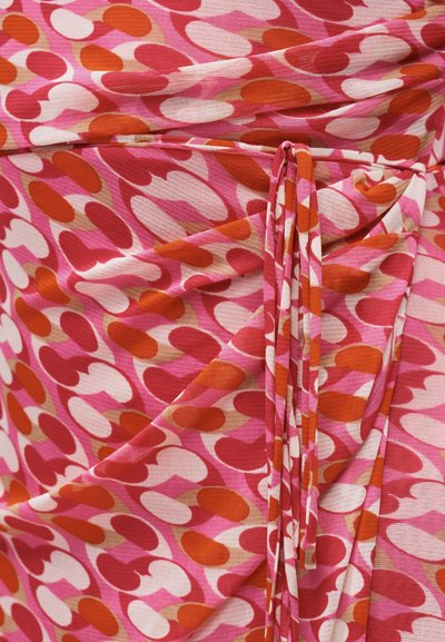 Κοντινό πλάνο ροζ υφάσματος με αφηρημένο μοτίβο από κόκκινα, πορτοκαλί και λευκά σημάδια σε σχήμα νεφρού και μια δεμένη υφαντή ζώνη.
