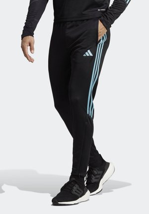 Zwarte sportbroek met lichtblauwe drie-streep accenten langs de zijkanten, gemaakt van rekbaar materiaal met ritszakken.