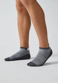 Graue Knöchelsocken aus einem strukturierten Stoff, mit einem dunkelgrauen Design und einem helleren Fersen- und Zehenbereich.