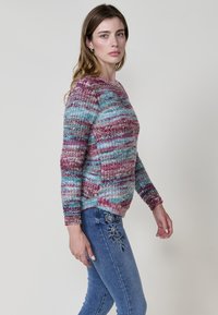 Suéter de punto multicolor con rayas azules, rosas y moradas; escote redondeado, mangas largas y diseño intrincado en el dobladillo.