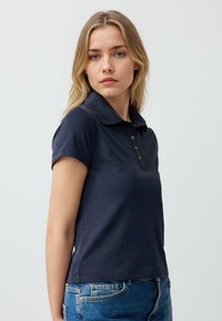 Polo a maniche corte blu navy con colletto e patta a tre bottoni, realizzato in tessuto morbido con una silhouette leggermente aderente.