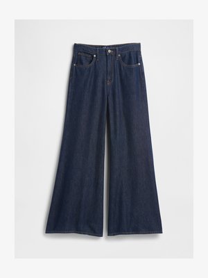 Jeans de ganga escuros de perna larga com uma cintura alta, apresentando cinco bolsos, um fecho frontal com botão e detalhes de costura visíveis.