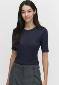 Tummansininen lyhythihainen paita, jossa on pyöreä pääntie, valmistettu sileästä kankaasta, yhdistetty harmaisiin muotosaumoihin. Siisti muotoilu, ei kuvioita.