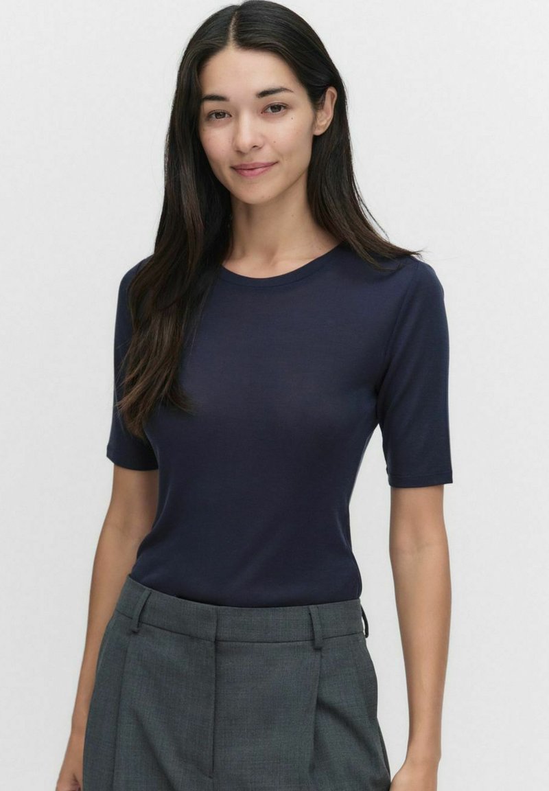 Tummansininen lyhythihainen paita, jossa on pyöreä pääntie, valmistettu sileästä kankaasta, yhdistetty harmaisiin muotosaumoihin. Siisti muotoilu, ei kuvioita.