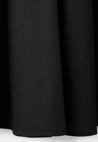 Gros plan d'un tissu noir à texture lisse suspendu en plis doux sur un fond clair.