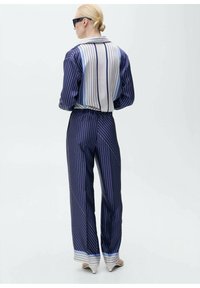 Completo a righe composto da top con colletto e pantaloni a vita alta in blu navy e azzurro, realizzato in un tessuto morbido e con un design a gamba affusolata.