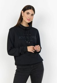Sweatshirt noir avec un col cheminée, cordon de serrage et texte imprimé "LAISSEZ NOUVELLES AVENTURES BERLIN." Tissu texturé avec une coupe décontractée.