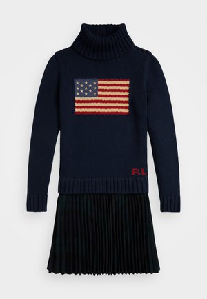 Suéter de punto azul marino con cuello alto acanalado, que presenta un motivo de la bandera de EE. UU. en rojo, blanco y azul. Incluye las iniciales bordadas en rojo "R.L." y una falda negra con plisados.
