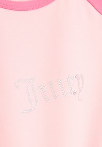 Roze katoenen top met een ronde halslijn, afgewerkt met contrasterende roze randen en een "Juicy"-ontwerp in zilveren rhinestones.