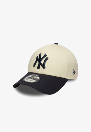 Beige Mütze mit schwarzem Schirm, vorne mit einem dunkelblau gestickten New York Yankees Logo und einem New Era Logo an der Seite.
