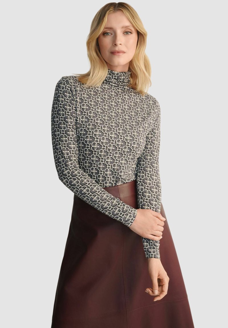 Czarna bluzka z długim rękawem i golfem w geometryczny biało-czarny wzór, w połączeniu z burgundową spódnicą; dopasowany krój z gładką teksturą.