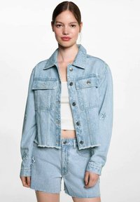 Ljusblå denimjacka med en kortad design, silverknappar, dubbla bröstfickor och stjärnbroderi på ärmarna, ihop med matchande shorts.