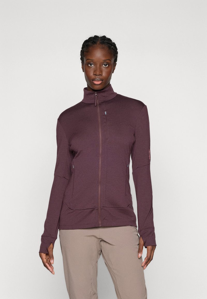 Giacca a zip bordeaux con colletto alto, maniche lunghe e cuciture piatte. Presenta due tasche con zip e un tessuto texturizzato per il calore.