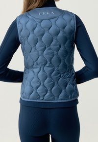 Chaleco acolchado azul marino con un cuello redondo, dobladillo acanalado y textura suave. Presenta sutiles acentos verticales en la parte posterior.