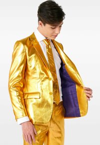 Completo metallico dorato con una texture lucente, caratterizzato da un giacca a un petto, cravatta abbinata, pantaloni e fodera viola nella giacca.