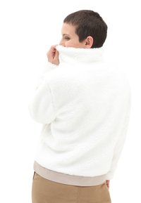 Hvid fleece pullover med høj krave, blød tekstur og en lav beige kant. Bagfra vises en afslappet pasform og sænkede skuldersømme.