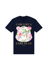 Marinblå bomullströja med en färgglad blommönster och ett björnhuvud med texten "VÅGA SOM EN KÄRLEKSBJÖRN" i guld. Året "1982" ingår.