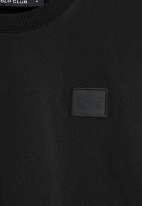Schwarzer Sweatshirt mit geripptem Rundhalsausschnitt, ausgestattet mit einem strukturierten schwarzen quadratischen Patch mit der Prägung "POLO CLUB" auf der Vorderseite. Weiches Material.