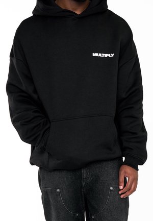 Zwarte hoodie met een voorzak in kangoeroestijl, een capuchon met trekkoorden en witte tekst "MULTIPLY" op de borst. Zacht, gestructureerd materiaal en een comfortabele pasvorm.