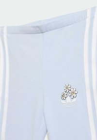 Ανοιχτό μπλε φόρμα παντελόνια με λευκές λωρίδες στα πλάγια, με κεντημένο σχέδιο τριών λουλουδιών πάνω από ένα καράβι στην αριστερή πλευρά του γοφού.