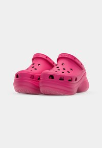 Rosefargede klipper med ventilasjonsdeler og bakstropp. Laget av lett materiale med teksturert såle for godt grep. Holdbare og lette å rengjøre.