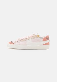 Rosa och beige lädersneakers med en vit swoosh-logotyp, mjuka snören och en strukturerad rosa hälaccent; lågprofil och rund tådesign.