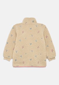 Polaire beige avec broderie florale en bleu et rose. Col montant, manches bordées de poignets, et ourlet rose en bas. Texture douce.