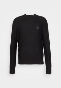 Pull noir à manches longues col rond avec maille texturée et petit patch logo carré sur la poitrine gauche.