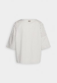 Blouse blanche ample à fines rayures noires verticales et manches larges trois-quarts, vue de dos sur un fond uni.