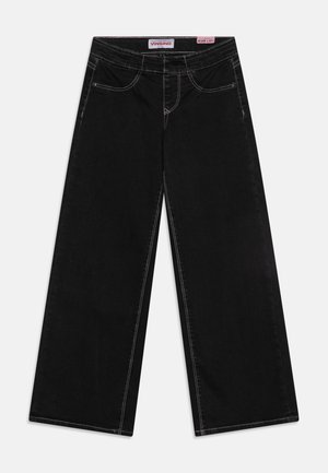 Melni plati džinsi ar kontrastējošiem baltiem šuvumiem, piecu kabatu dizains un augsta vidukļa līnija. Materiāls izskatās mīksts ar gludu tekstūru.