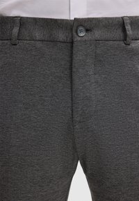Pantalons texturés gris avec fermeture à bouton, poches en biais et coupe ajustée, ornés d'un léger motif chiné.