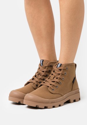 Bottes de cheville en toile marron avec semelles en caoutchouc, bout rond et laçage à l'avant. Comprend une étiquette de logo et des coutures renforcées pour la durabilité.