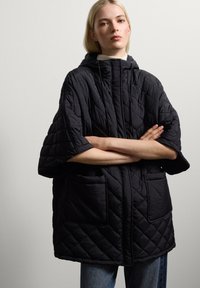 Schwarze gesteppte Jacke mit weit geschnittenem Schnitt, Kapuze und großen Fronttaschen. Verfügt über ein strukturiertes Muster und einen durchgehenden Frontverschluss.
