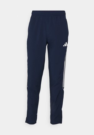 Marine blauwe sportbroek met een elastische tailleband, taps toelopende pasvorm en ritsen bij de boorden. Heeft drie witte strepen aan de zijkant en logo-accenten.