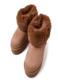 Botas de tobillo de ante color beige con un suave cuello de piel sintética marrón, que cuentan con una gruesa suela plataforma para mayor altura y comodidad.