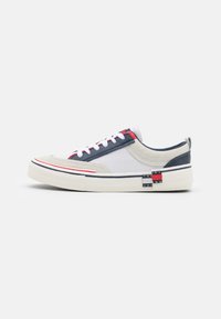 Sneakers con una combinazione di materiali superiori bianchi, grigi e blu navy, con accenti rossi e blu, pannelli testurizzati e un dettaglio del logo in evidenza.