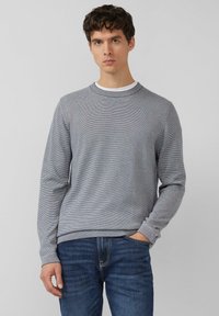 Grijs gestreepte trui met een ronde hals, geribde manchetten en zoom, gedragen over een wit T-shirt. De stof lijkt glad en licht van gewicht.