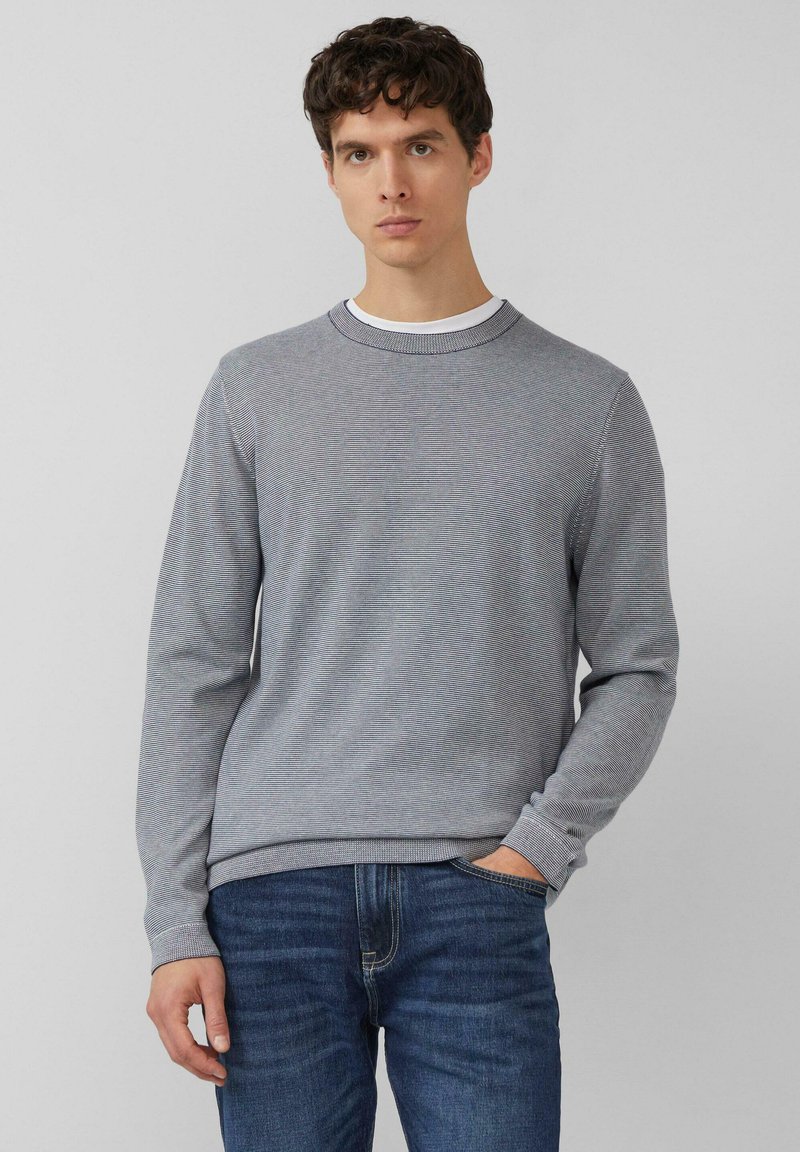 Grijs gestreepte trui met een ronde hals, geribde manchetten en zoom, gedragen over een wit T-shirt. De stof lijkt glad en licht van gewicht.